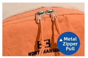 Close-up of durable metal two-way zippers and textured orange nylon fabric on backpack