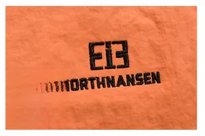 Close-up of black brand embroidery on premium orange fabric with textured detail