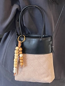 Chic two-tone bucket bag with quilted patterns and wooden bead tassel, worn crossbody