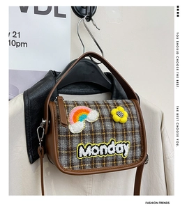 Detail der Vintage-Karotasche mit Monday-Stickerei und süßen Blumen-Aufnähern