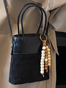 Elegant black crossbody bucket bag with mixed textures and decorative wood bead tassel