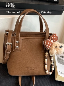 Chic brown pebbled leather bucket bag with top handles and adjustable crossbody strap