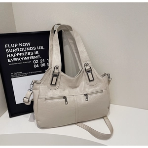 Detail of creamy off-white PU leather tote bag featuring front dual zipper pockets