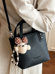 Fashionable black pebbled leather bucket bag with a cute bear charm for women