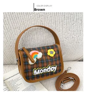 Detailansicht der braunen Tweed-Handtasche mit Karomuster und Monday-Stickerei sowie Blumen