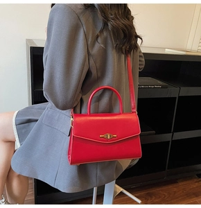 Detailed view of red leather handbag featuring a vintage gold twist lock on the flap cover