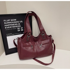 Close-up of wine red tote bag showing faux leather texture and vintage metal zippers