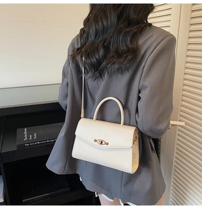 Chic beige crossbody bag with metal lock shown on a model wearing a grey blazer jacket