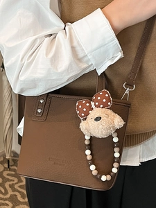 Chic brown lychee leather bucket bag with plush bow charm and beaded handle for women