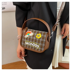 Detailansicht einer Vintage-Karotasche mit Monday-Stickerei auf einem schwarzen Blazer