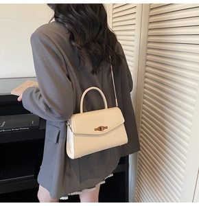 Close-up of minimalist cream white crossbody bag with vintage gold twist lock on model