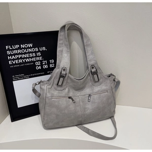 Detail showing grey faux leather texture and vintage bronze hardware on the tote bag