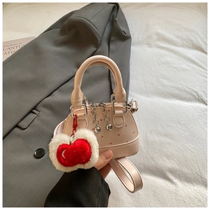 Detailed shot of pink polka dot shell bag with silver chain and cherry charm accessory