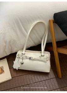 Gros plan d'un sac sous le bras en cuir verni blanc avec pendentif cœur et étoile