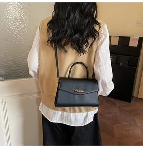 Detailed view of a black leather crossbody bag with a vintage gold metal twist lock buckle