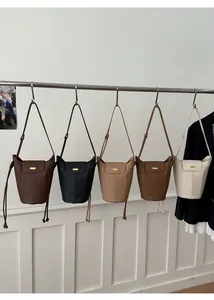 Vue détaillée de cinq sacs seaux en plusieurs couleurs avec des logos en métal doré élégants