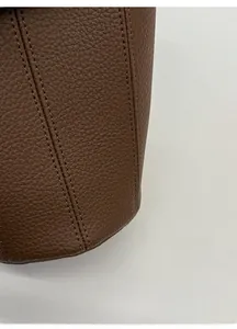 Vue détaillée du sac seau en cuir grainé marron montrant les finitions et les coutures