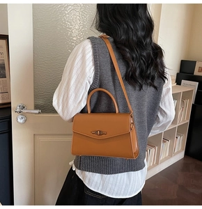 Side view of caramel brown leather handbag worn by model in a cozy vintage setting