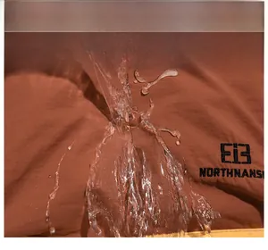 Détail macro du tissu marron imperméable avec broderie argentée et gouttes d'eau