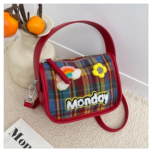 Detail der roten Karo-Umhängetasche mit Monday-Stickerei und niedlichen Regenbogen-Patches