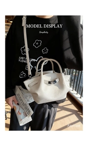 Détail d'un sac seau blanc cassé en cuir grainé avec une boucle métallique élégante