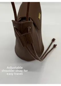 Détail de la bandoulière réglable et texture grainée du sac seau marron avec zip