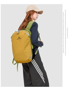 Vista laterale di un grande zaino outdoor color zenzero e verde indossato da una modella