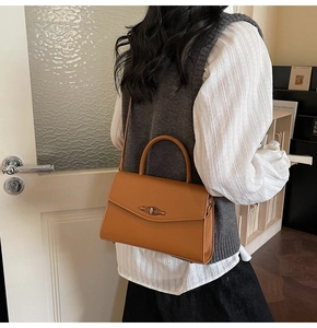 Detail of caramel leather crossbody bag with vintage metal turn-lock and handle