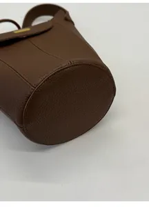 Gros plan sur la base large ronde et la texture cuir grainé marron du sac seau