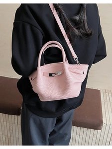 Sac seau en cuir rose à texture litchi porté en bandoulière avec un fermoir rotatif en métal