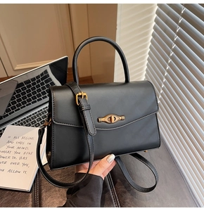 Detailed view of the black textured handbag with gold twist lock and metal feet
