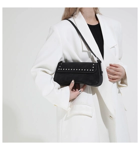 Close-up of black leather underarm bag with silver rivet details and slim shoulder strap