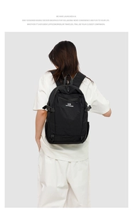 Rear view of a double-decker black Oxford backpack on model with logo and side straps