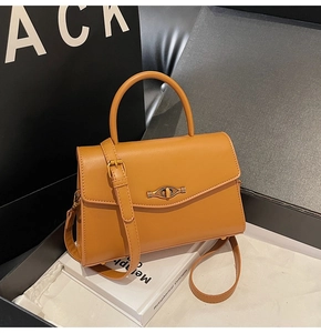 Detailed close-up of caramel leather handbag with distinctive gold eye-shaped metal lock