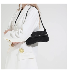 Detail of black underarm bag featuring silver rivets and elegant asymmetric silhouette