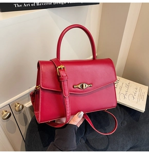 Detail of burgundy leather handbag featuring a vintage gold twist lock and smooth texture