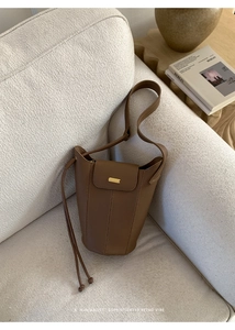 Détails du sac seau en cuir marron grainé avec coutures verticales et boucle dorée