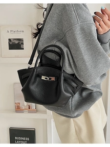 Détail du sac seau en cuir grainé noir avec boucle argentée porté par un mannequin