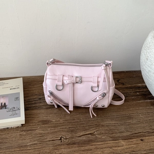 Rosafarbene Vintage Motorradtasche mit Metallreißverschlüssen auf dunklem Holztisch