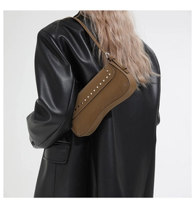Detail view of a vintage brown leather saddle bag with metallic rivets on a model