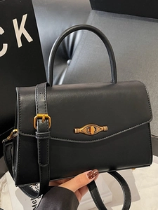 Elegant black matte leather handbag with gold eye-shaped lock and adjustable strap
