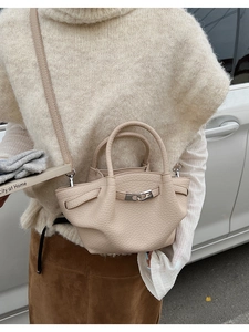 Mini sac seau en cuir grainé beige avec fermoir argenté porté par un mannequin