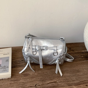 Detail der silbernen Metallic-Zylindertasche mit Reißverschlüssen und langen Fransen
