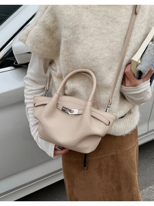 Détail du sac seau en cuir grainé beige avec une boucle en métal argenté élégante et raffinée