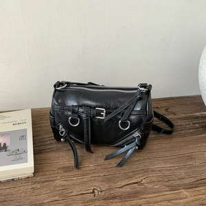 Detail der schwarzen glänzenden Zylindertasche mit silbernen Reißverschlüssen und Fransen