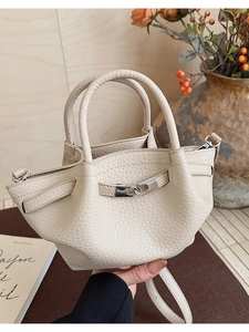Détail d'un sac seau en cuir crème avec texture litchi et boucle métallique argentée