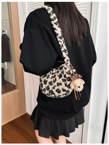Detail of plush leopard print shoulder bag with cute bear charm on a model
