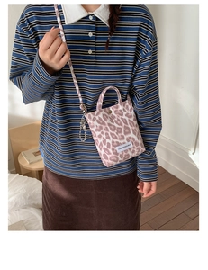 Détail du sac cabas en toile à imprimé léopard rose avec bandoulière et décor métal