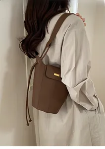 Détail d'un sac seau en cuir marron avec boucle dorée porté par un mannequin