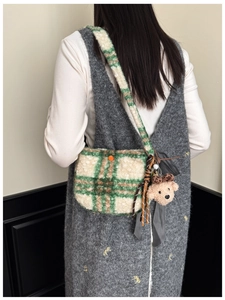 Detail of plaid plush crossbody bag with orange button and cute teddy bear charm accessory